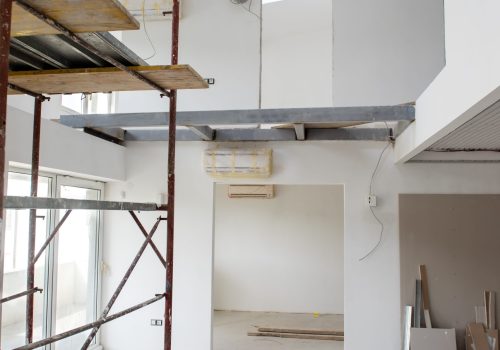 interior of construction site with scaffolding in a large modern unfinished duplex apartment